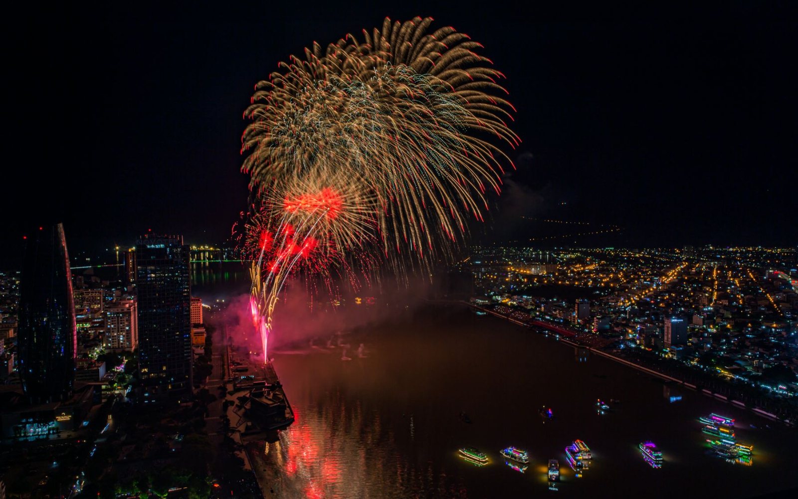 National Day Fireworks in Saigon: A Private Rooftop to Watch From 1 Fireworks bursting over the river at night, seen from above the city