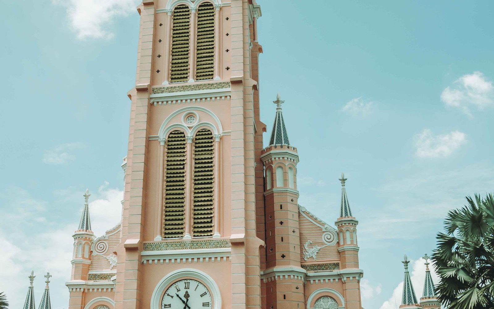 The pink Tan Dinh Church with its clock tower against a blue sky in District 3, Saigon