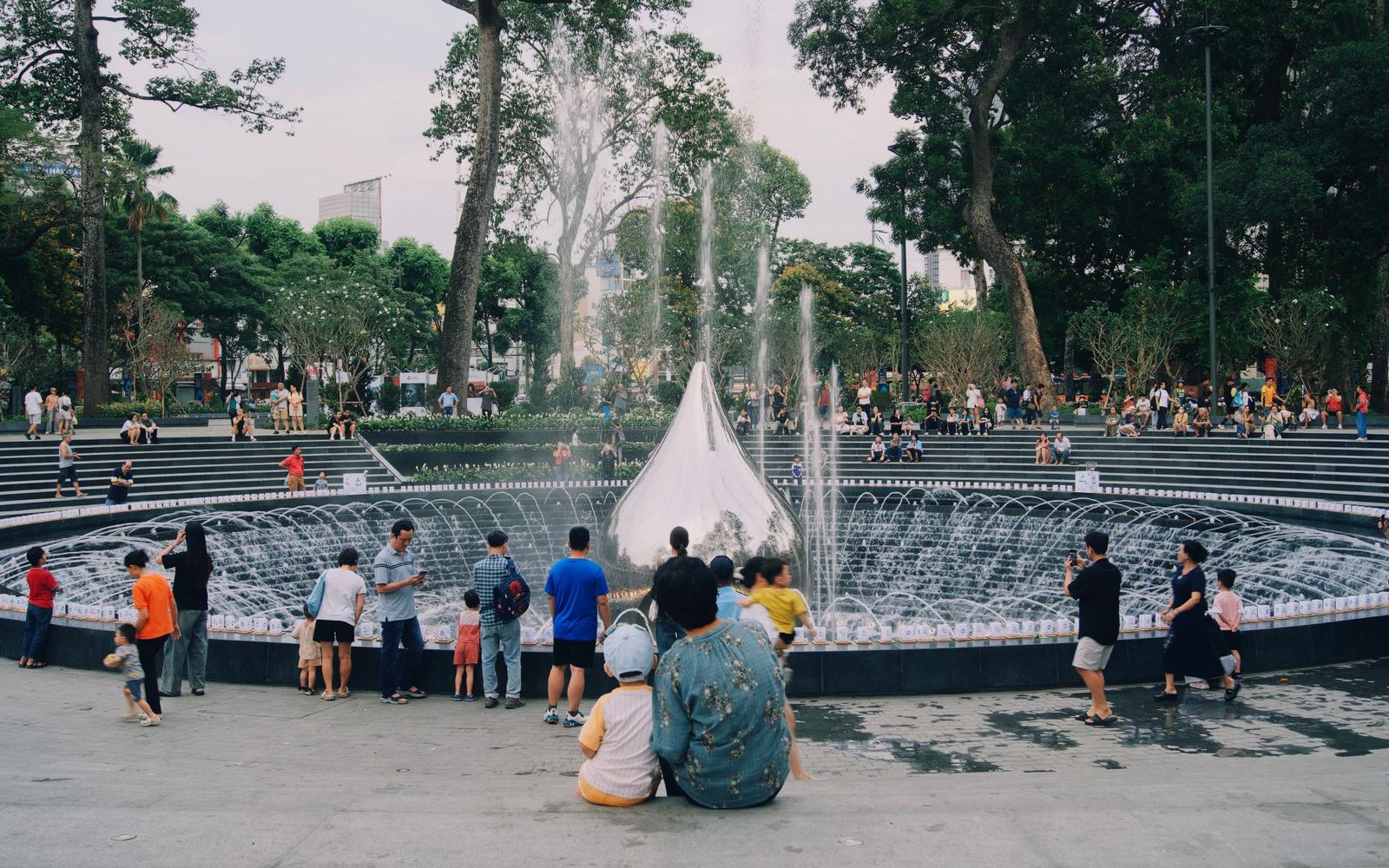 Young locals gathering around a fountain in a District 3 park near Turtle Lake, Saigon at dusk